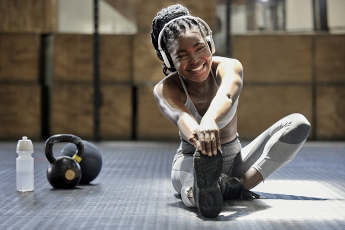 Mujer realizando estiramientos dinámicos en el gimnasio para mejorar la circulación sanguínea y prevenir lesiones después del ejercicio.  