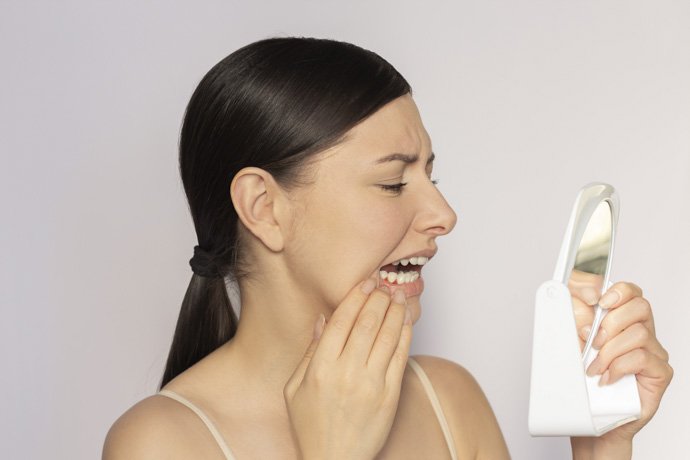 Mujer se revisa manchas blancas en encías