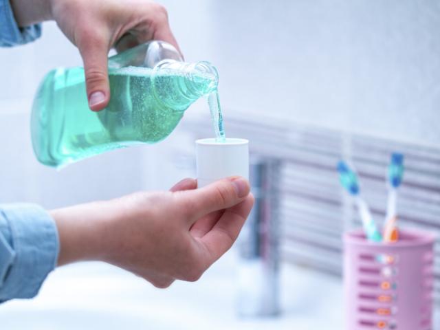 Persona utilizando enjuague bucal